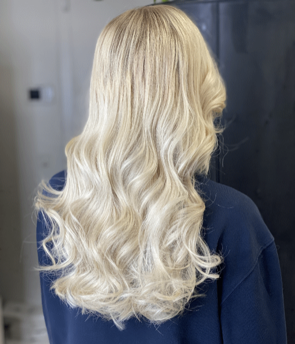 Frauenfrisur von hinten – lange platinblonde Haare mit sanftem Wellenstyling