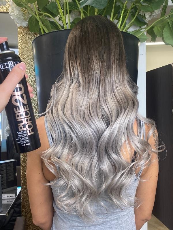 Echthaar Tressen Frauenfrisur von hinten. Lange gewellte Haar in Grau-Silber Balayage mit Lockenstyling